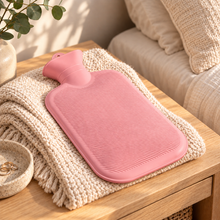 Pastel Pink 2L hot water bottle resting flat on knitted blanket