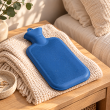 Blue 700mL hot water bottle lying flat on knitted throw